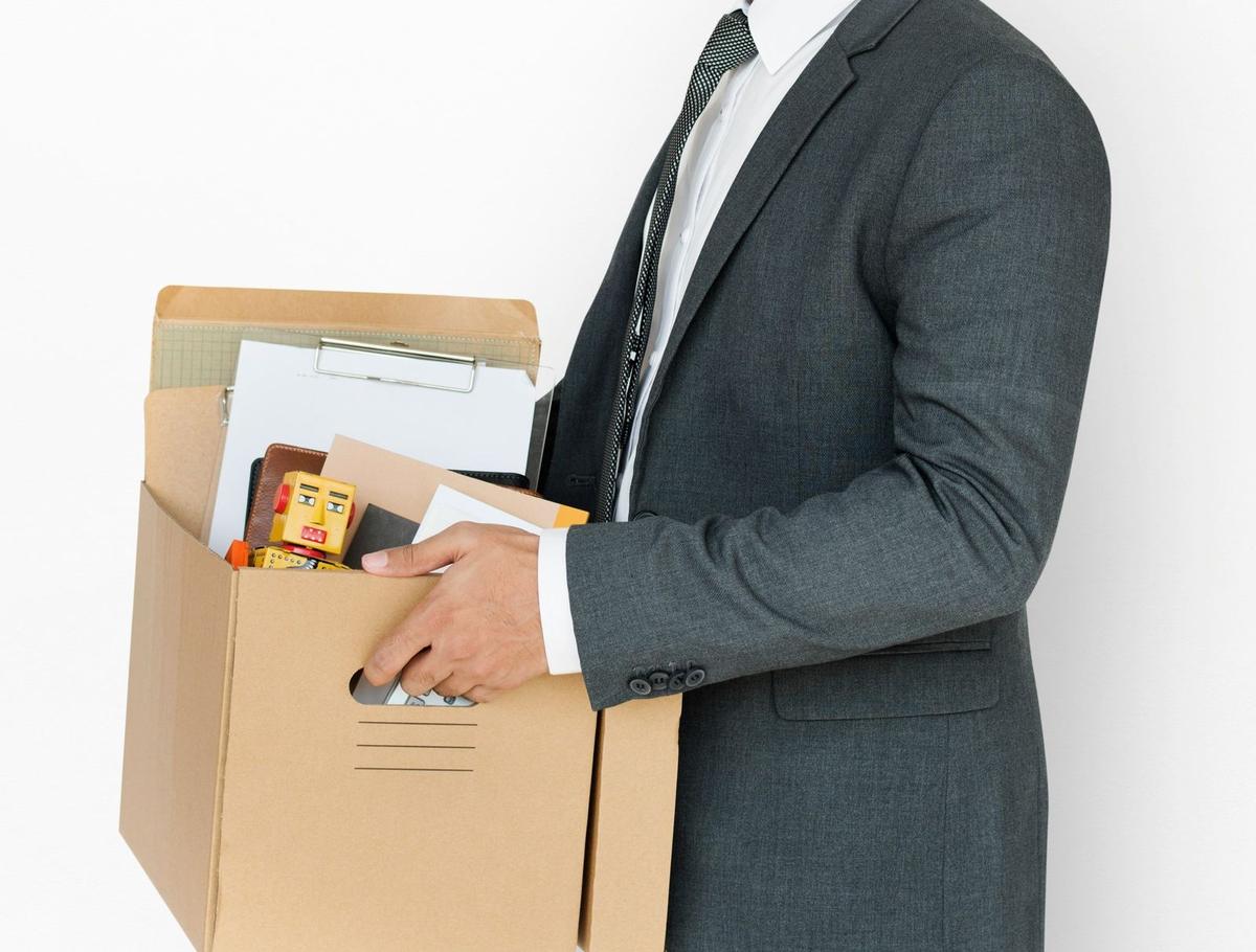 man in suit holding a box of belongings