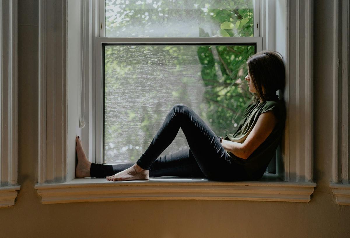 An image of a young woman sat looking out the window