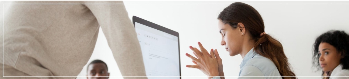 A picture of a lady with fingers intwined at her computer desk looking stressed