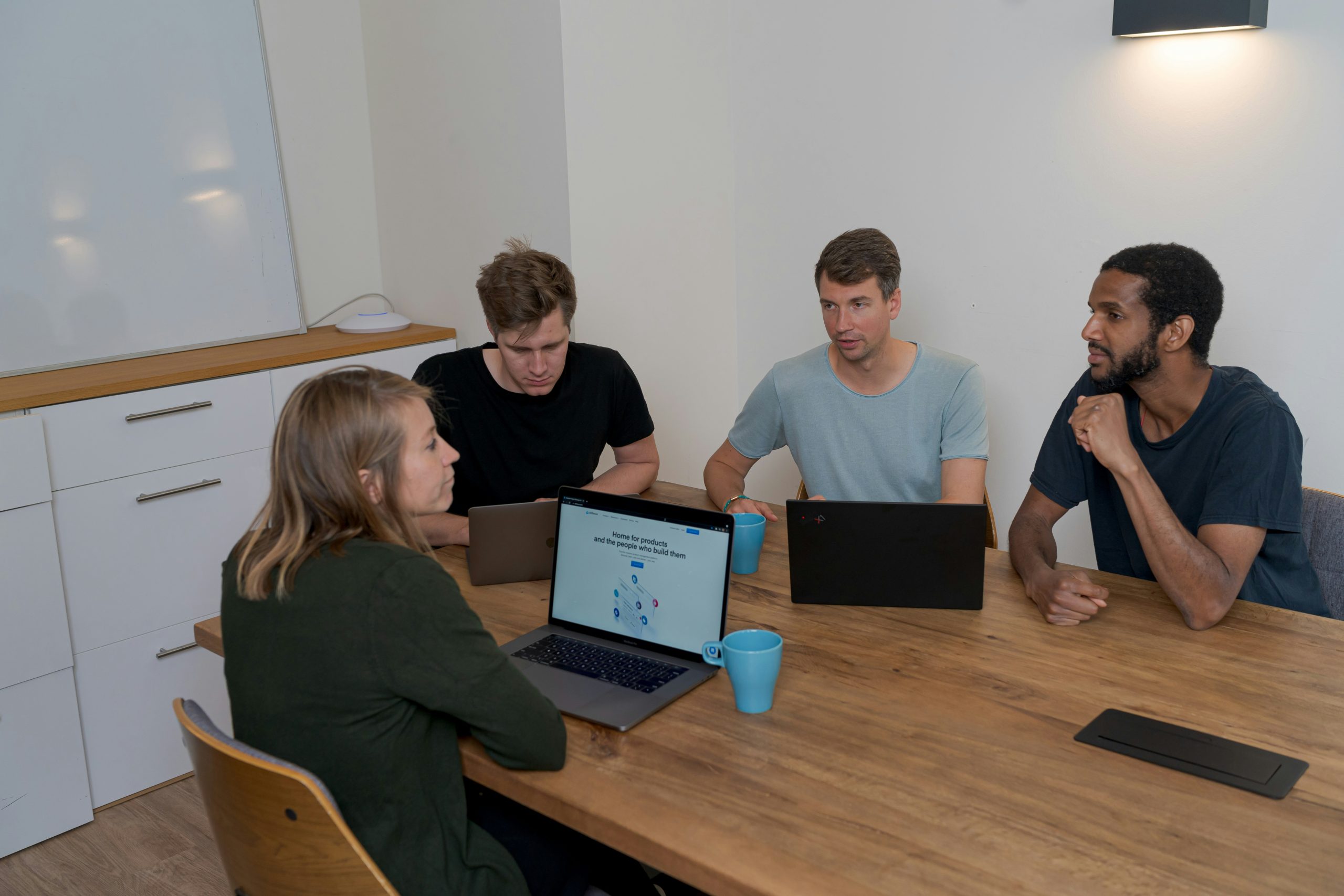 Picture of 4 people - 3 men and 1 woman -in an office, they are clients discussing website usability