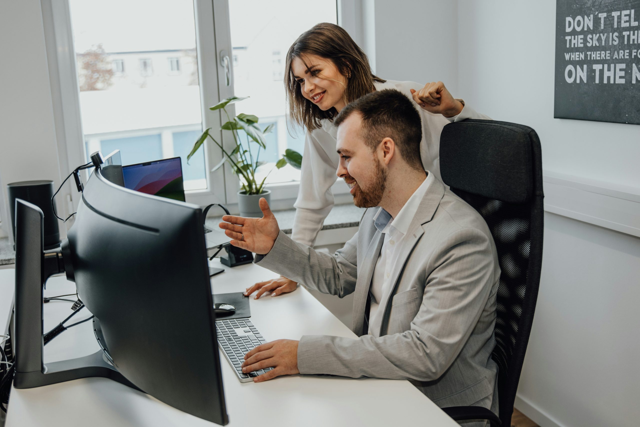An image of two colleagues male and female looking at a computer screen interacting