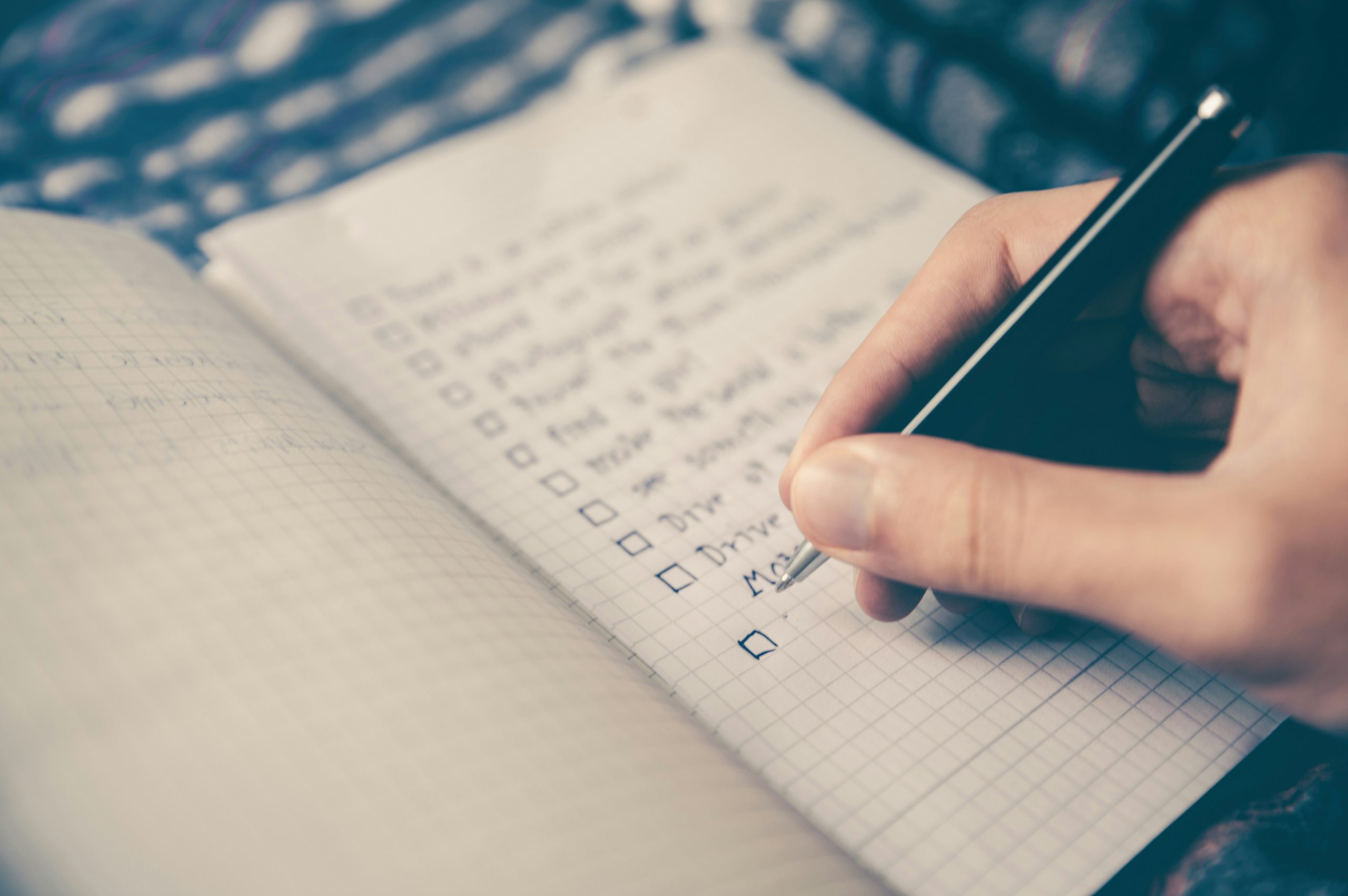 an image of a hand holding a pen writing a to do list of steps to manage risk