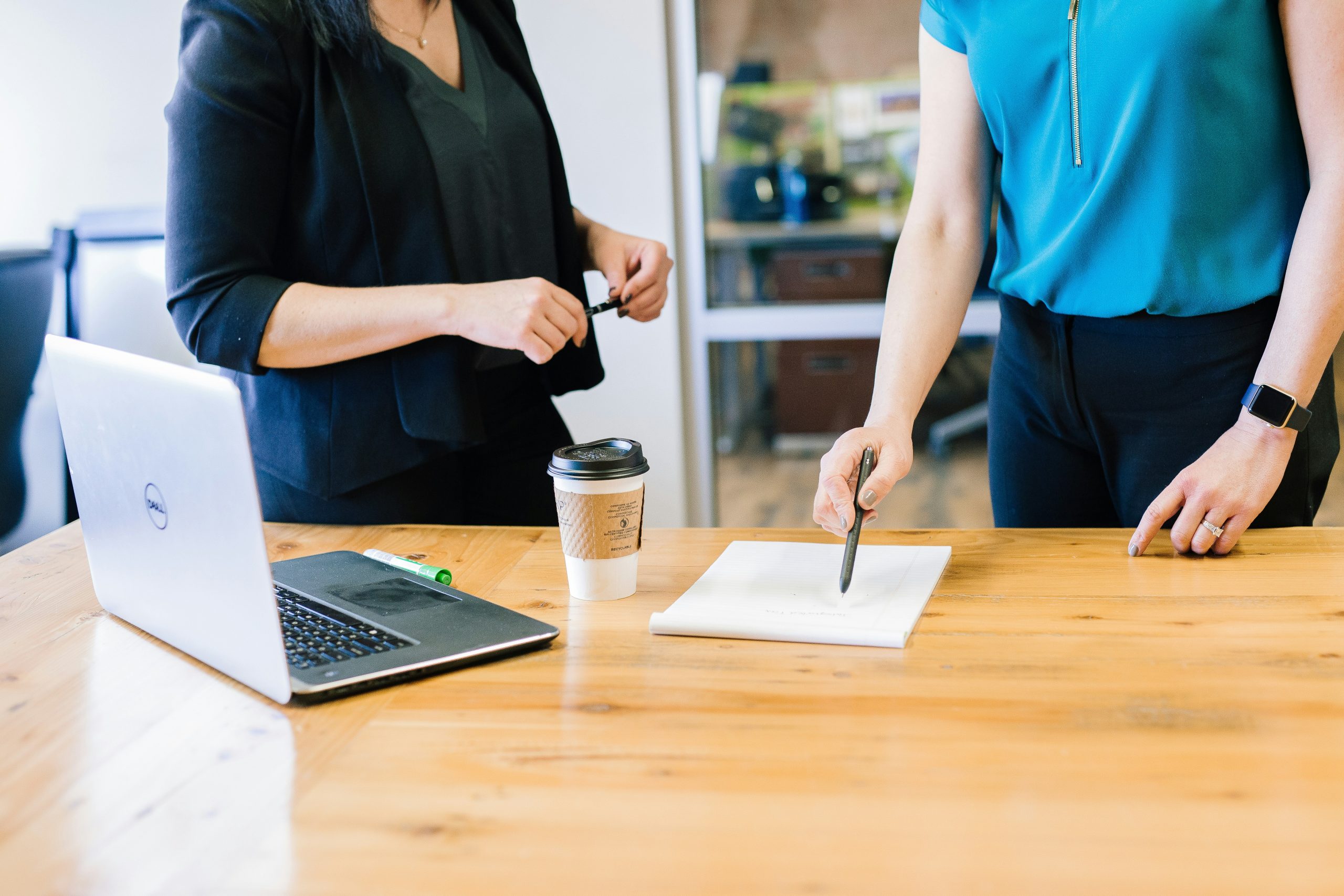 An image of two women discussing a document they are pointing to with a pen on a desk symbolising insurance